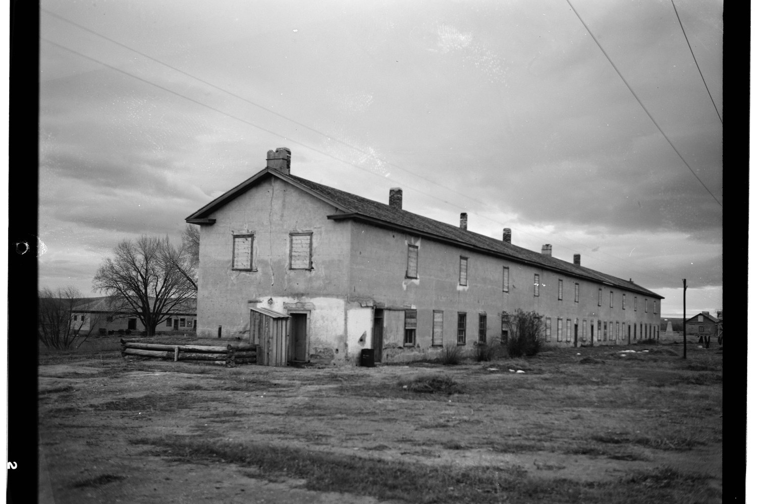 The long cavalry barracks at Fort Laramie with its two storeys of porch, in black and white.